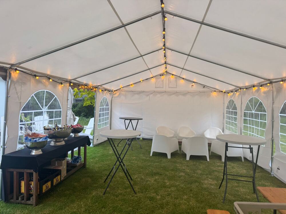 Partytent met statafels, buffettafel en lichtslingers.