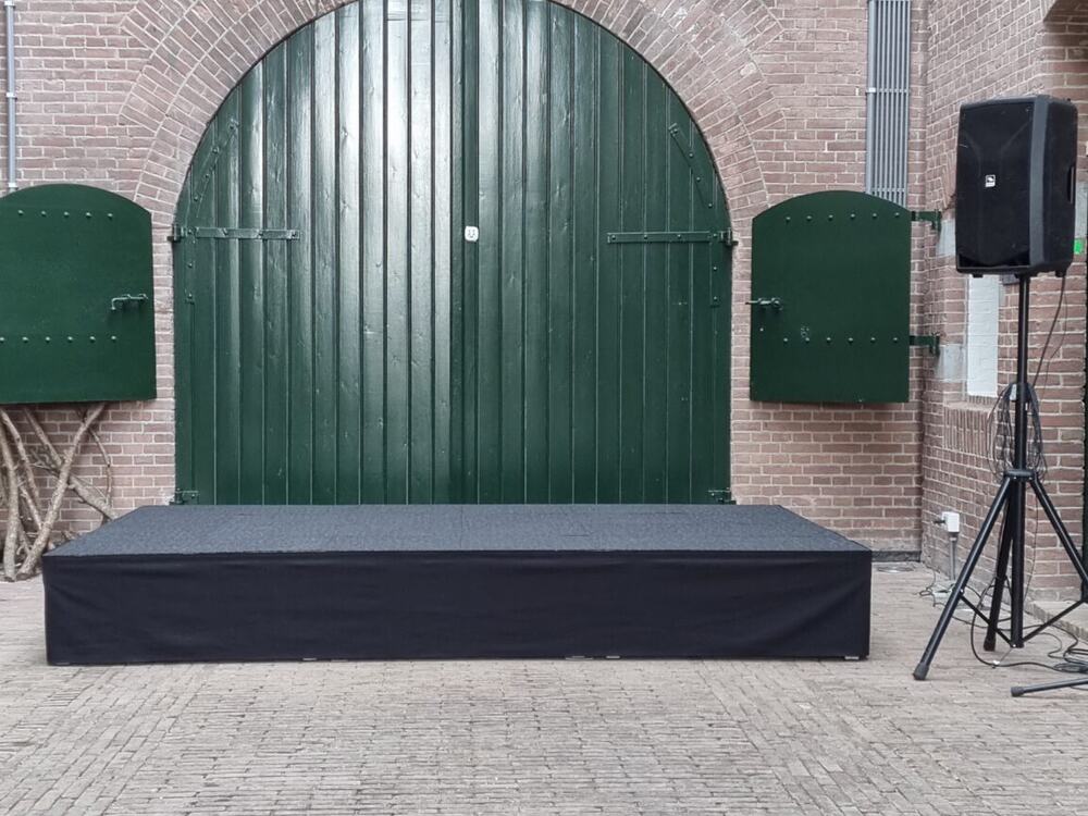 Podium met rok en geluid, opgebouwd tegen de gevel.