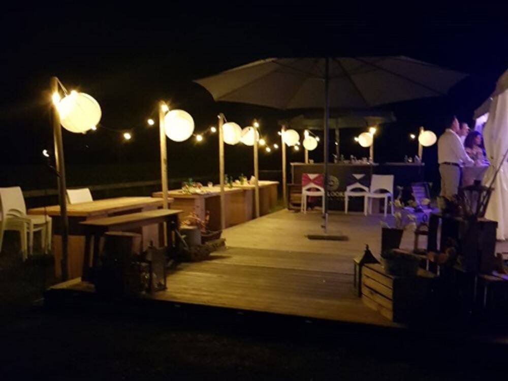 Vlonder met bar en bollampen, een uur na zonsondergang.